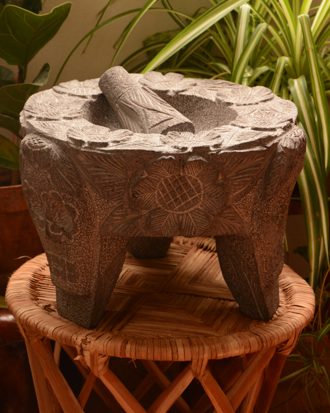 Molcajete labrado de piedra volcánica con calaveras y flores.