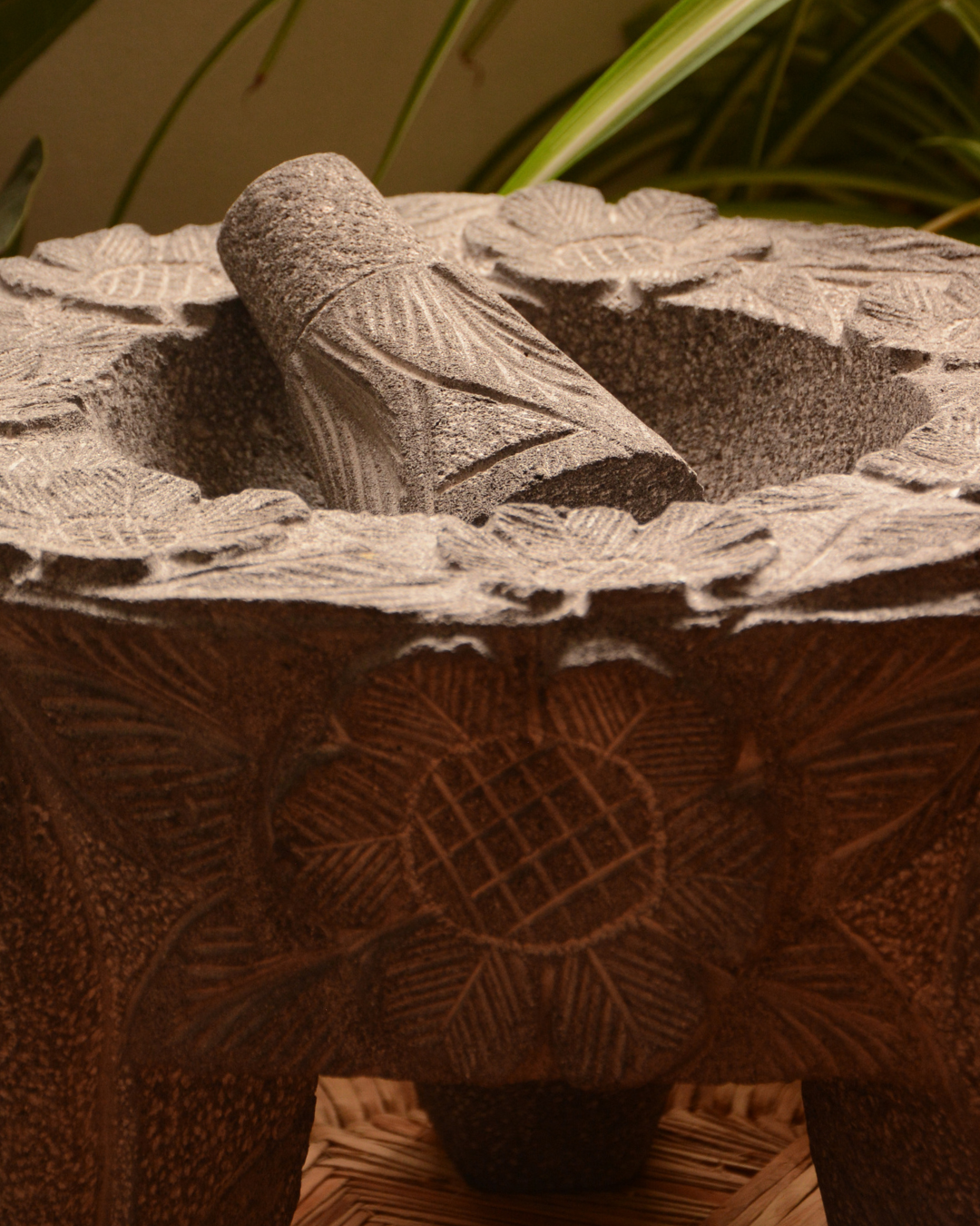 Molcajete labrado de piedra volcánica con calaveras y flores.