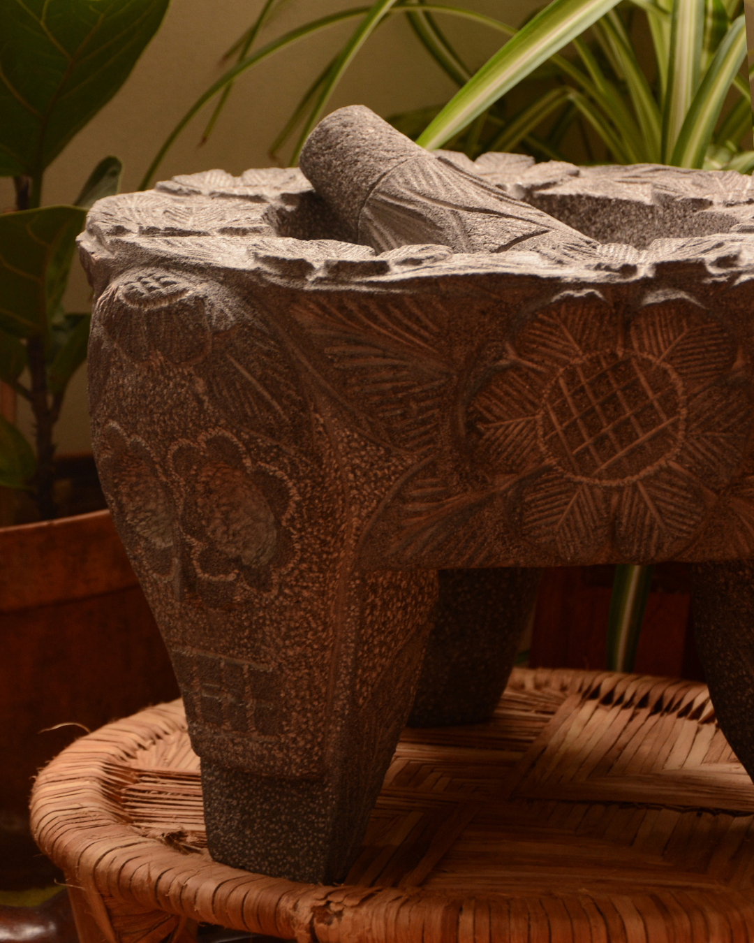 Molcajete labrado de piedra volcánica con calaveras y flores.